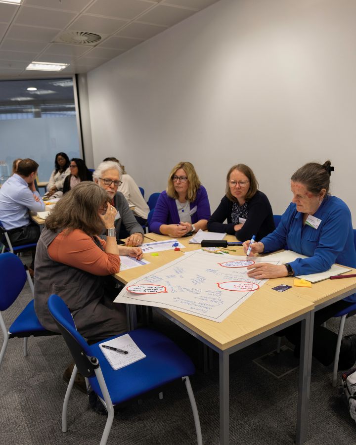 A group of people sitting around a table in a seminar room.