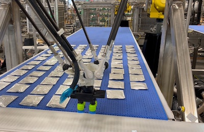 The Delta Robot picks pouches off a conveyor, then orients and places them into a tray pattern on a mass conveyor that feeds the tray-loading robot.