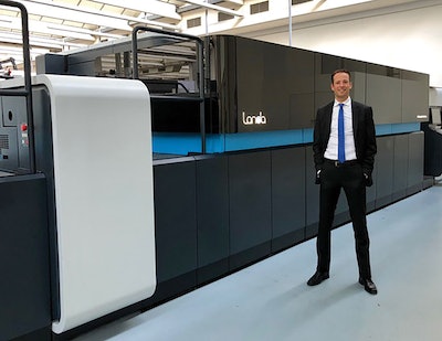 Oliver Bruns, CEO of the Edelmann Group, stands in front of the LANDA S10 press, which uses a method of digital printing called nanography.