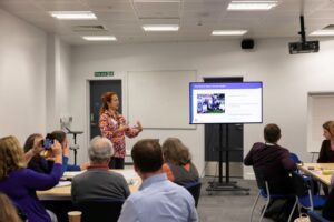 A woman presents in front of a seminar room giving a workshop. Photograph from VitaeCon2024. 